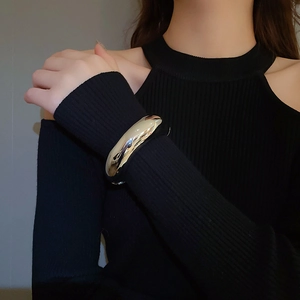 Polished silver metal cuff bracelet shown on model with black knit sweater detail