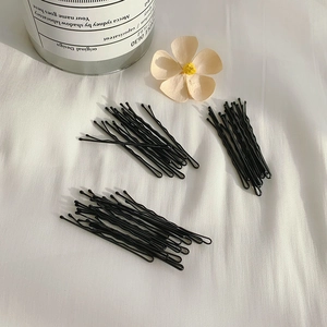 Minimalist black metal hair pins set displayed on soft fabric with floral decor