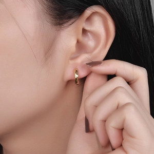 Orecchino a cerchio dorato minimalista con superficie strutturata indossato dalla modella