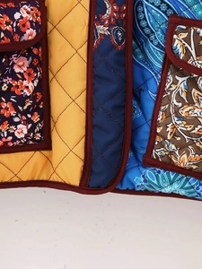 Macro shot of quilted patchwork vest with floral patterns and vibrant contrast binding