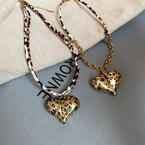 Detailed view of leopard print heart pendants with gold chains and leather cords