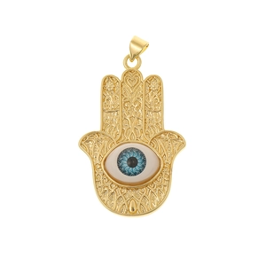 Macro shot of gold Hamsa Hand pendant with hollow patterns and blue evil eye detail