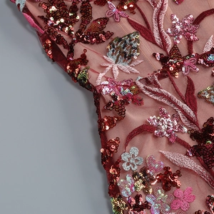 Close-up of intricate floral embroidery and sequins on burgundy mesh evening dress