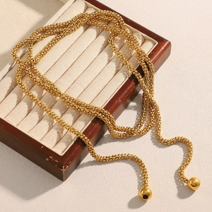 Close-up of 18K gold-plated beaded multi-layer chain draped on a wooden jewelry box