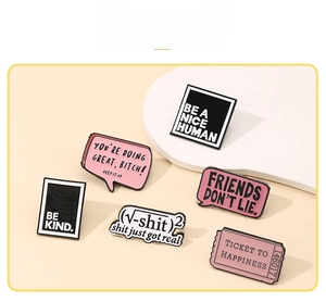 Close-up of set of six enamel letter pins with Be Kind slogan on geometric display stand