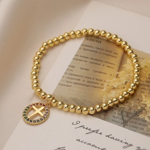 Goldenes Kugelarmband mit buntem Zirkonia Kreuzanhänger im religiösen Stil