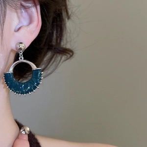 Close-up of model wearing a vintage dark green circular earring with a metallic finish