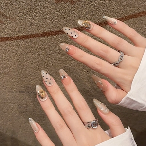 Handmade stiletto press-on nails with nude base, black dots, yellow gems and silver butterflies