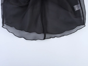 Détail de l'ourlet volanté et du tissu en maille sur le haut en organza noir à coutures