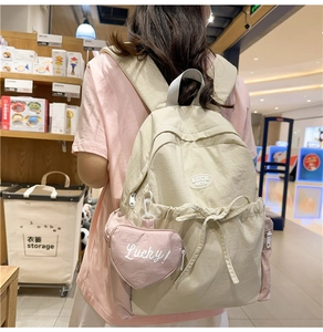 Detail of color-block nylon backpack with bow drawstring and pink heart pouch accessory
