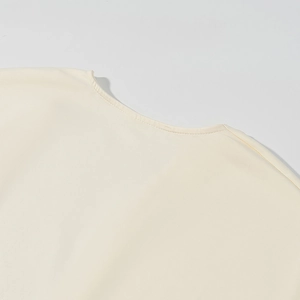 Dettaglio dello scollo in maglia crema che mostra le cuciture fini e la trama liscia