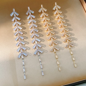 Detailed view of silver and gold leaf tassel earrings with zircon on champagne satin