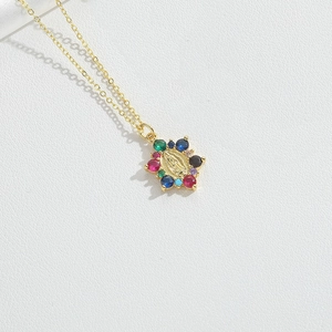 Macro shot of gold necklace pendant with Virgin Mary relief and multi-color zircon stones
