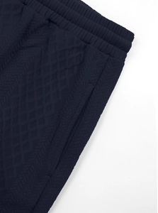 Detail of dark blue joggers with elastic waist and textured diamond jacquard fabric