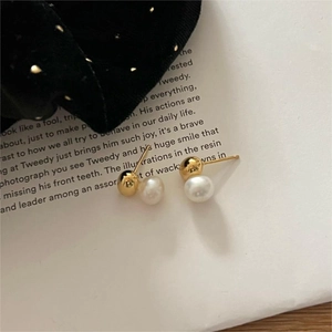 Detailed close-up of gold stud earrings with elegant white pearls on a vintage book