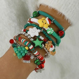 Close-up of layered Christmas charm bracelets with reindeer and Santa pendants on wrist