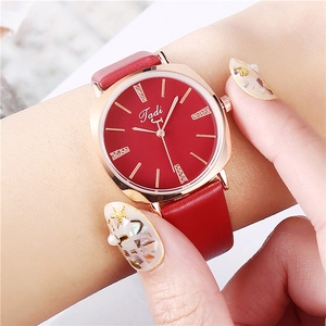 Detailed view of women's quartz watch with red dial, crystals and rose gold case on wrist