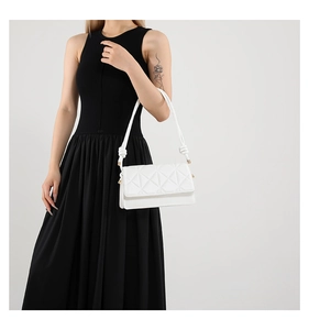 Detailed close-up of white quilted crossbody bag with geometric lattice pattern and knot detail