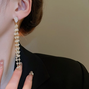 Close-up of long 18k gold plated tassel earrings with crystals on a model in a suit