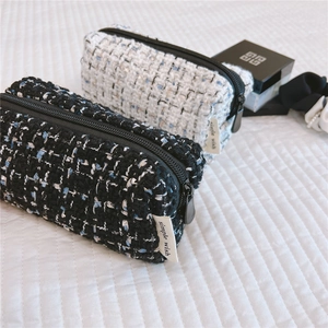 Detail shot of tweed fabric texture and simple wish label on the compact cosmetic pouch