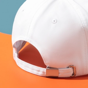 Close-up of a white cotton baseball cap showing adjustable silver metal strap buckle