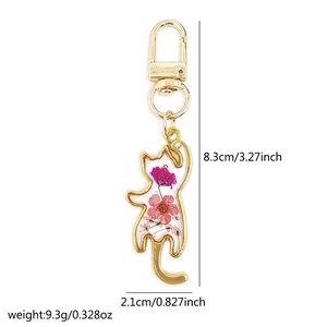 Detailed close-up of a cat-shaped resin pendant featuring purple dried flowers and gold hook