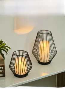 Detail of two Nordic black geometric iron lantern candle holders with LED pillar candles