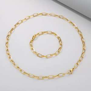 Unisex golden stainless steel paperclip chain necklace and bracelet set on grey surface