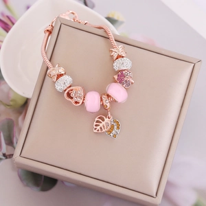 Rose gold beaded bracelet with pink glass beads and heart charms on a jewelry box