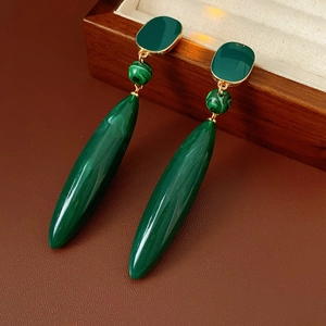 Macro view of vintage gold earrings with green malachite stone teardrop pendant