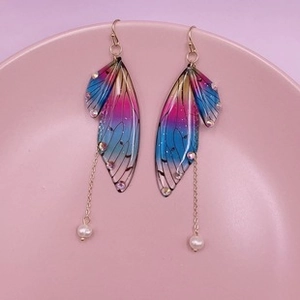 Macro shot of cicada wing earrings with colorful rhinestones and pearl drops