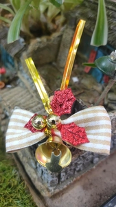 Close-up of linen stripe bow with red glitter holly leaves and golden bells decor