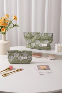 Detail of green cotton linen makeup bags with floral embroidery and gold zipper accents