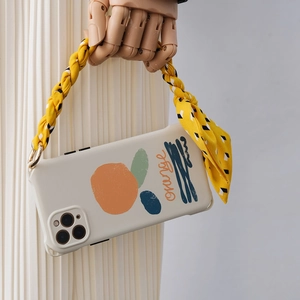 Detail of cream white phone case with orange prints and yellow floral fabric handle