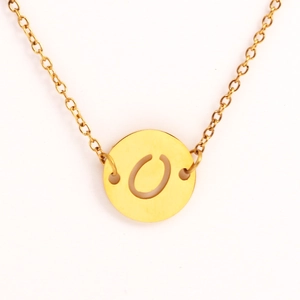 Détail d'un collier doré avec pendentif rond présentant une lettre O gravée et ajourée