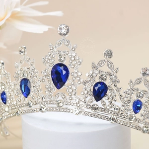 Detailed view of silver crown with clear rhinestones and large dark blue gemstones
