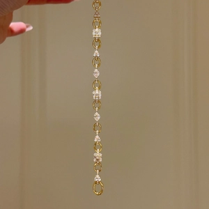 Detailed view of the gold chain bracelet with sparkling multi-shape cubic zirconia stones