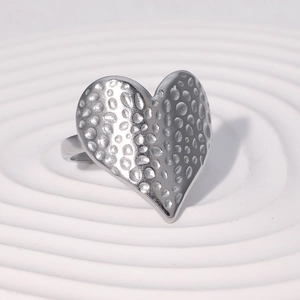 Minimalist silver heart ring with a hammered metal texture shown on a white pedestal