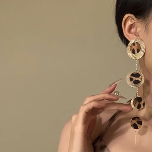 Exaggerated leopard print drop earrings with gold textured circles and fringe design
