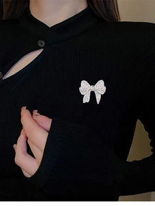 Detailed view of a silver bow brooch with sparkling zircons pinned on a black knit garment