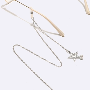 Detail of silver eyewear chain with star charms and pearls on sunglasses
