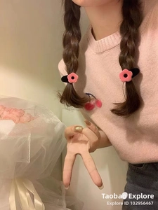 Dettaglio di fermagli per capelli a fiori in velluto rosa indossati su treccine nere