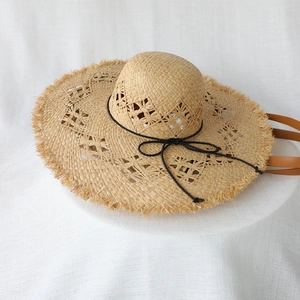 Natural woven raffia sun hat with wide frayed brim and black ribbon tie detail
