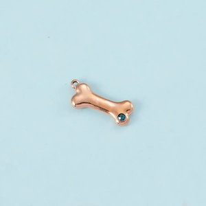 Macro detail of rose gold bone pendant with sparkling blue zircon stone and hanging loop