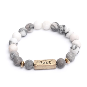 Macro-detail van yoga-armband van lavasteen met gegraveerde metalen Best-bedel