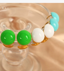 Macro shot of French style hemispherical stud earrings in green, white, and blue enamel