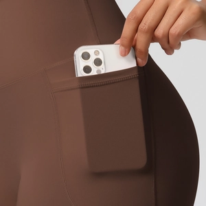 Detail of high-waist yoga shorts showing a functional side pocket with a smartphone inside