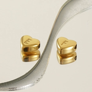 Macro shot of gold heart pendants with engraved letters E and F on 18K stainless steel