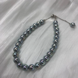 Detailed view of dark grey pearls with iridescent luster and silver adjustable clasp