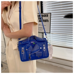 Detail of blue biker jacket shaped crossbody bag with silver studs and decorative zippers